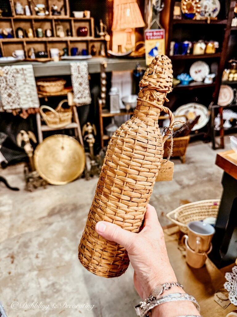 Vintage tall skinny demijohn bottle in hand at at antique store in Maryland.