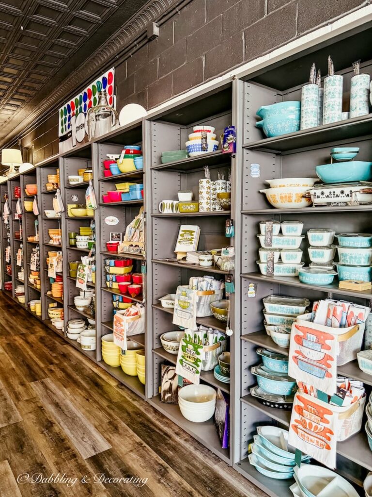 Wall of shelving inside JoRetro in Maryland filled and styled by color Pyrex displays in orange, green, blue, aqua and more.