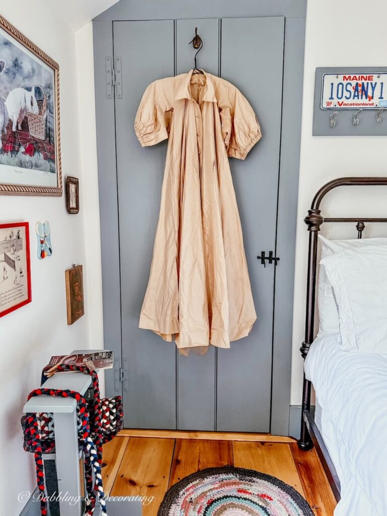 Thrifted beige antique taffeta gown hanging on vintage clothes hanger on bedroom door for thrifted bougie decor ideas.