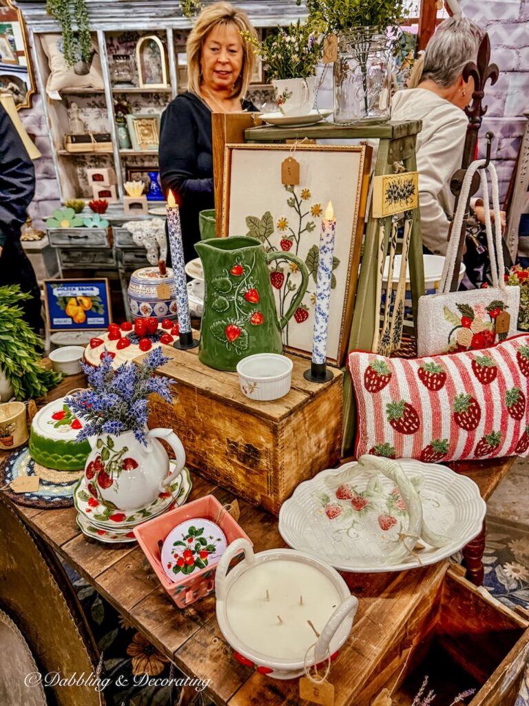 Vintage booth at Vintage Market Days styled with a strawberry collection of pitchers, dishes, candles, pillows, pictures, cake stand, and more.