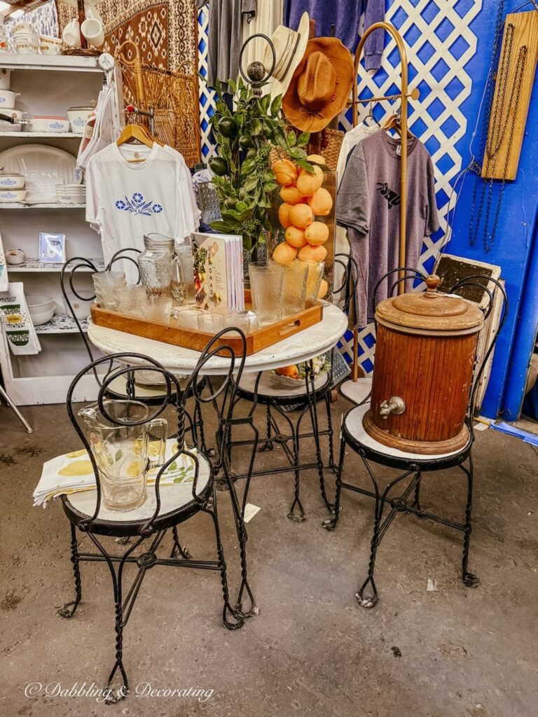 Vintage booth at Vintage Market Days with outdoor table and chairs with a lemonade tray and glassware and cooler.