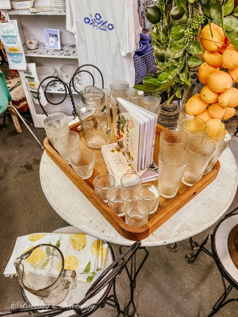 Vintage wooden tray on outdoor cafe wrought iron table with vintage glassware and lemons inside a vintage booth set up for spring.