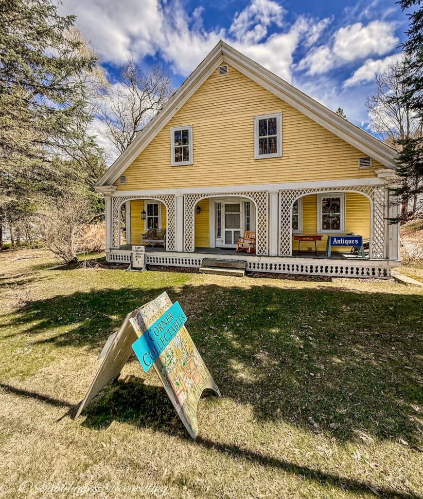 Old yellow farmhouse in Vermont with Antique sign in yard open today.