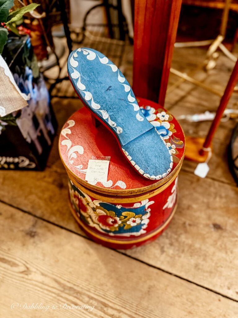 German vintage shoe shining box in bright red and blue with shoe on top in antique store.