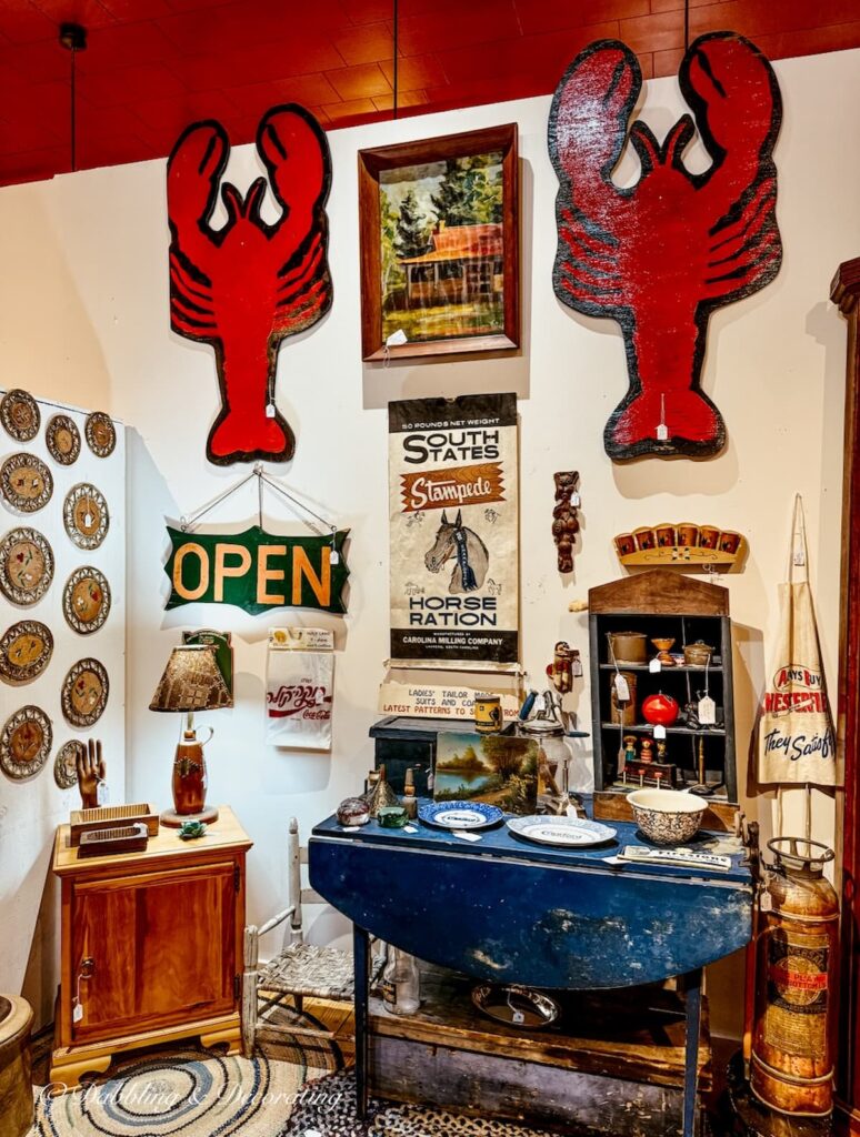 Vintage booth inside antique store with red lobsters on wall blue table and antiques on a solo antiquing trip to the Northeast Kingdom, Vermont.
