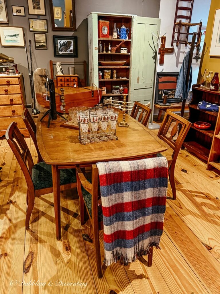 Vintage booth inside a Vermont antique store with dining table and chairs and a plaid blanket grounding the booth.