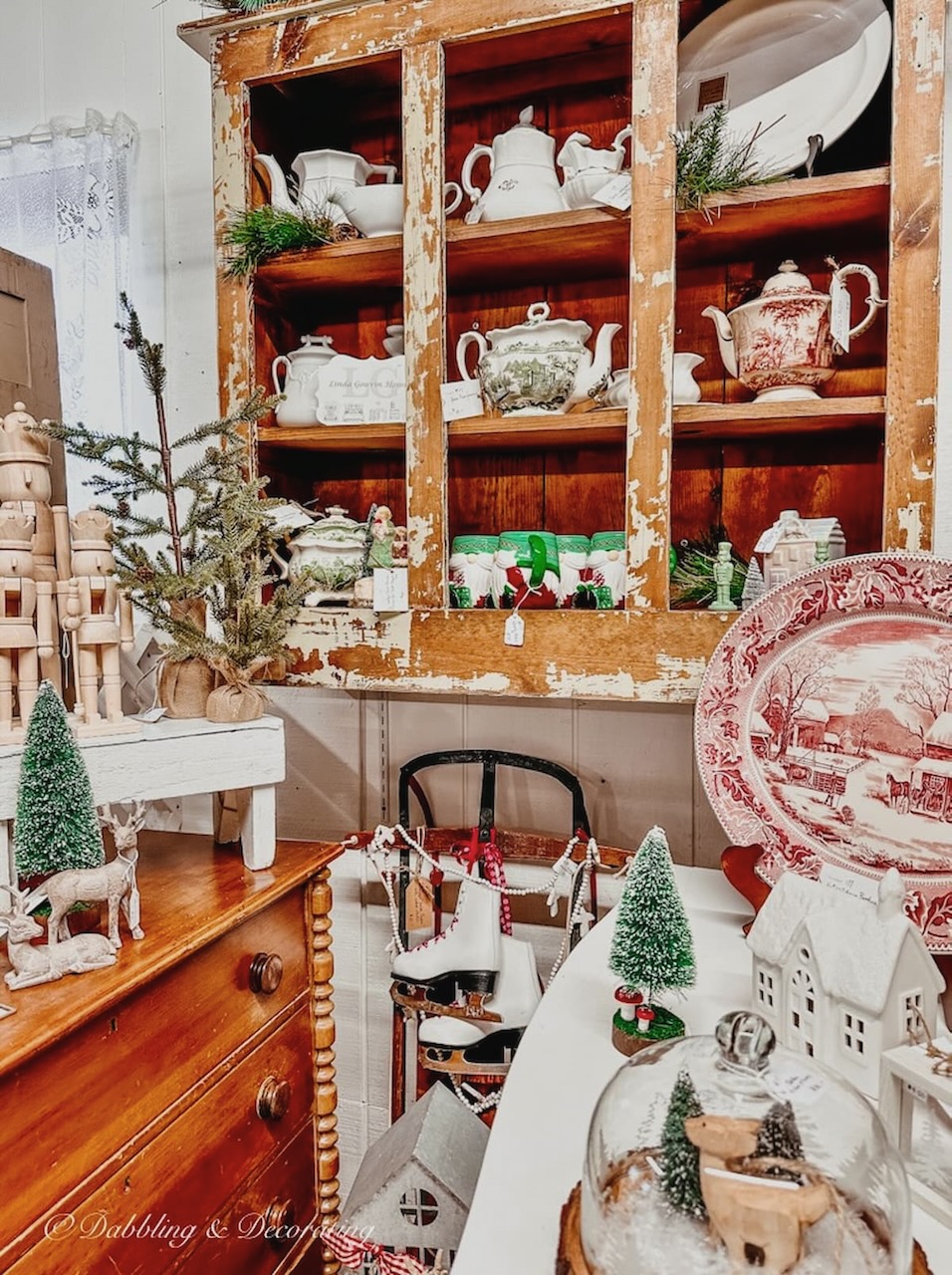 Antique booth display with red and white transferware and one green and white transferware tea pitcher.
