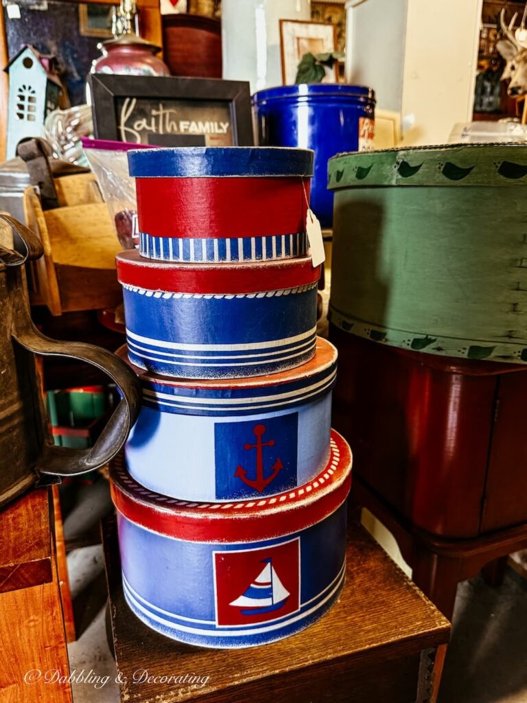 A stack of red, white, and blue boxes from large to small for Heritage Americana decor ideas to look for in antique stores.