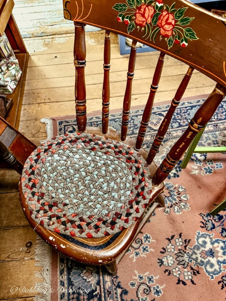Old wooden chair with braided rug seating cushion in antique store in Amish Country.