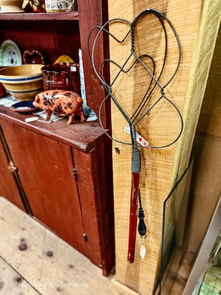 Primitive Red and metal antique rug beaters hanging on wall in antique store.
