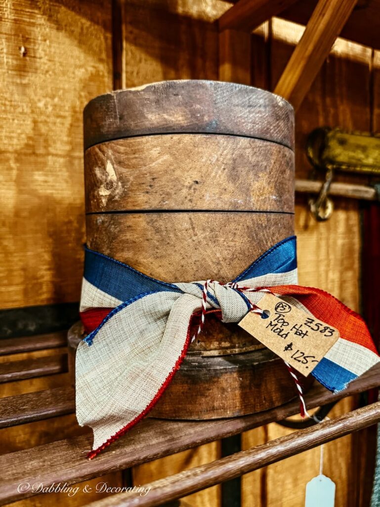 Antique top hat mold with old red, white, and blue ribbon tied round it in antique store in Amish Country.