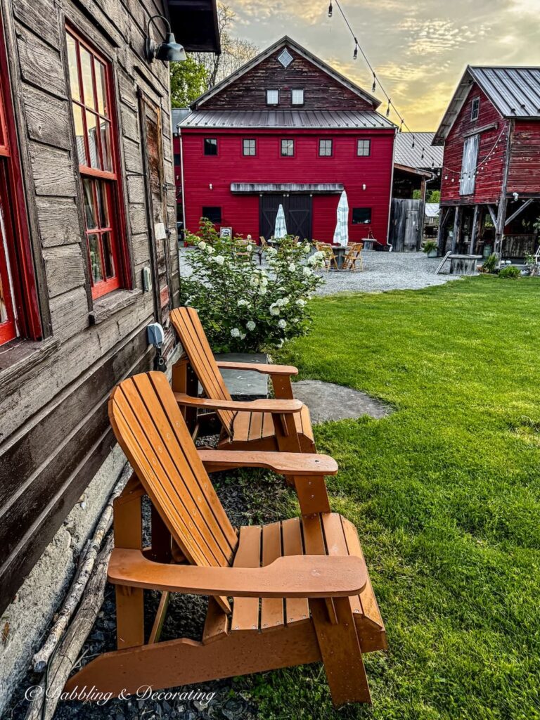 The wedding venue at Owl's Hoot Barn in Coxsackie, NY.  Adirondack chairs and red barns on outdoor landscape.