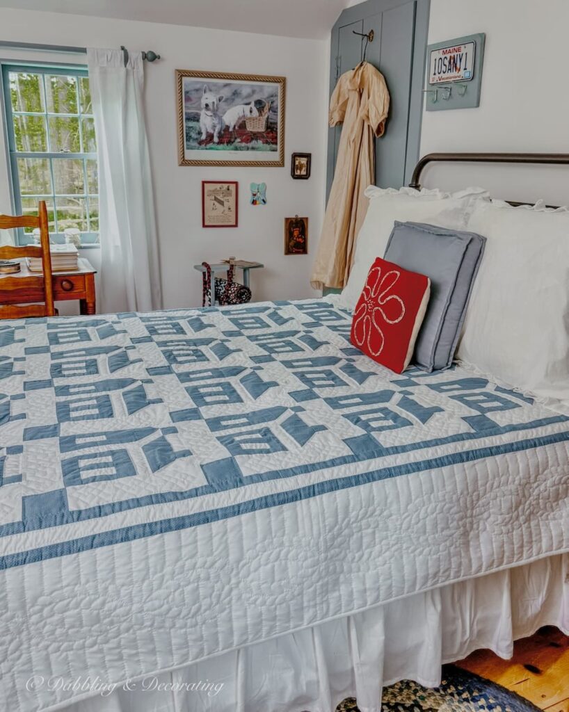 Blue and white Amish quilt on wrought iron bed in small guest bedroom at home in Maine.