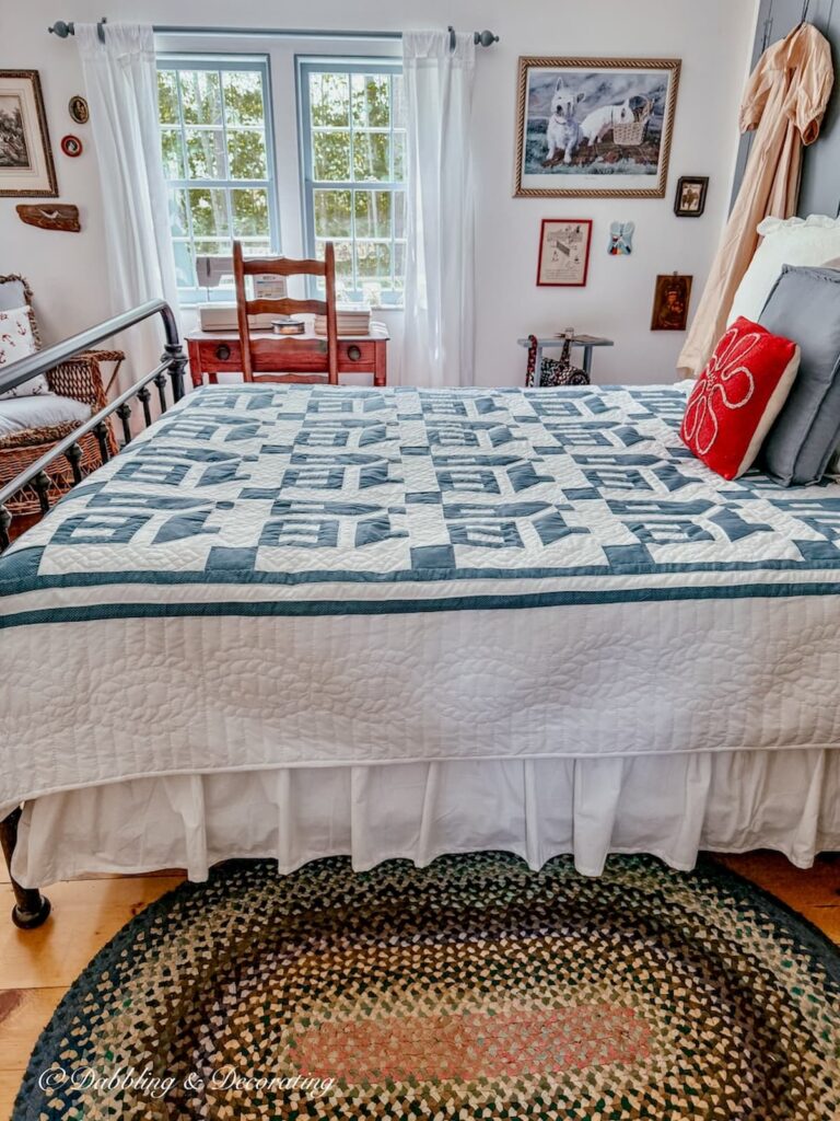 Small guest bedroom with wrought iron bed styled with a blue and white Amish house quilt.