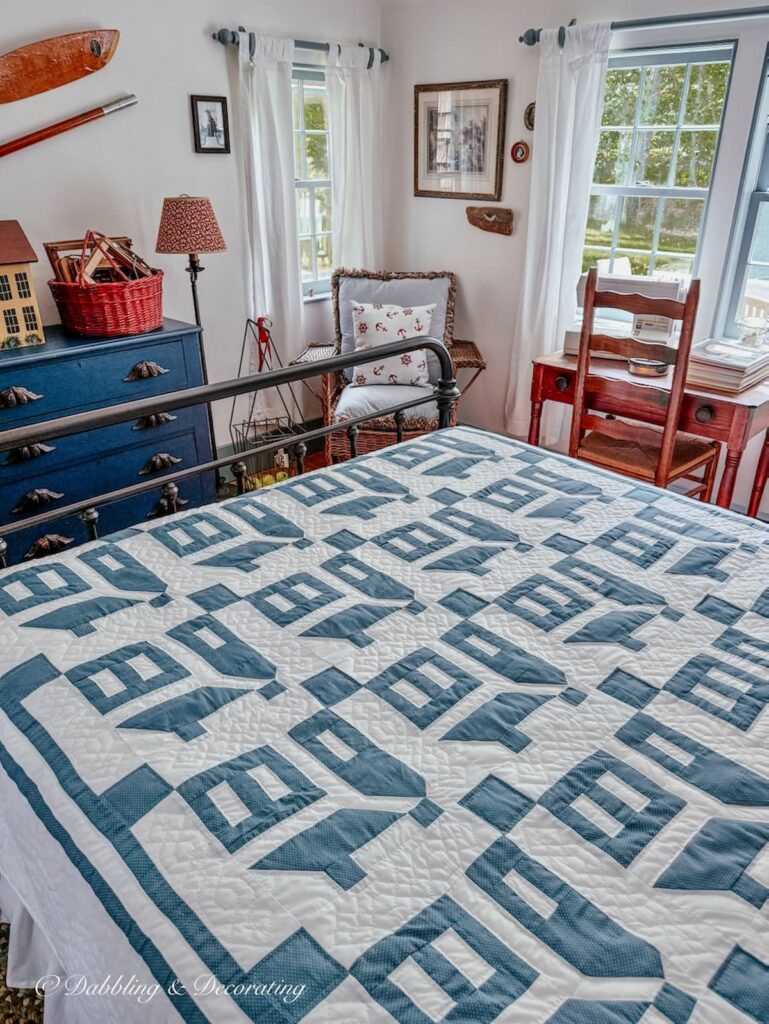 Blue and white Amish quilt on wrought iron bed in small guest bedroom at home in Maine.