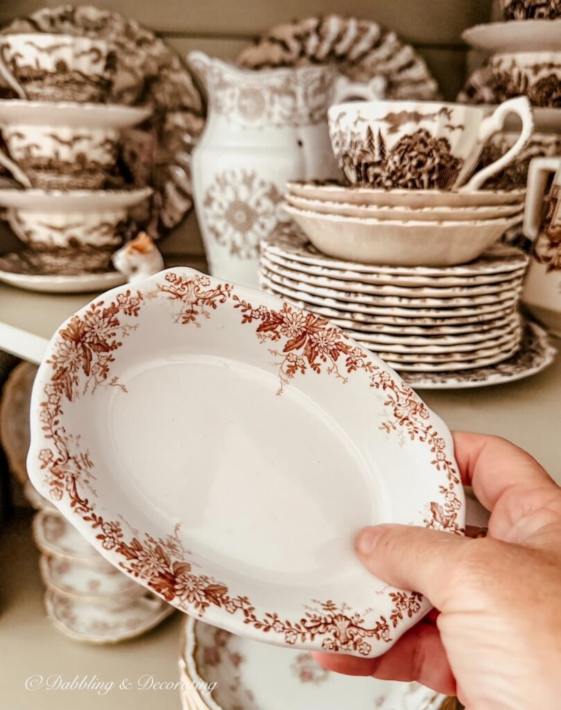 Brown and white transferware soap dish in hand in front of transferware collection.
