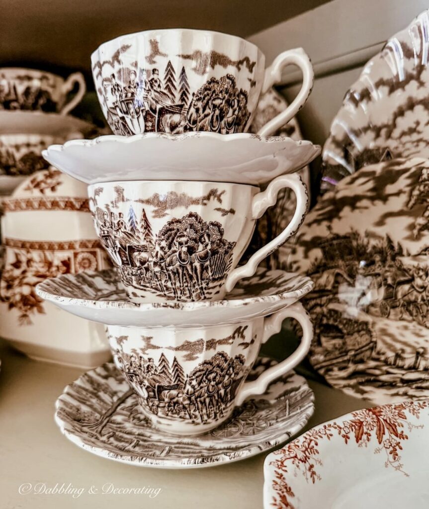 Three tea cups and saucers stacked in vintage hutch up close.