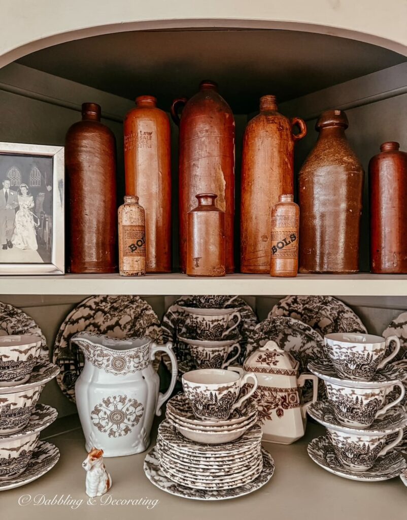 Vintage corner built-in hutch with brown and white transferware collection and brown jug collection displayed.
