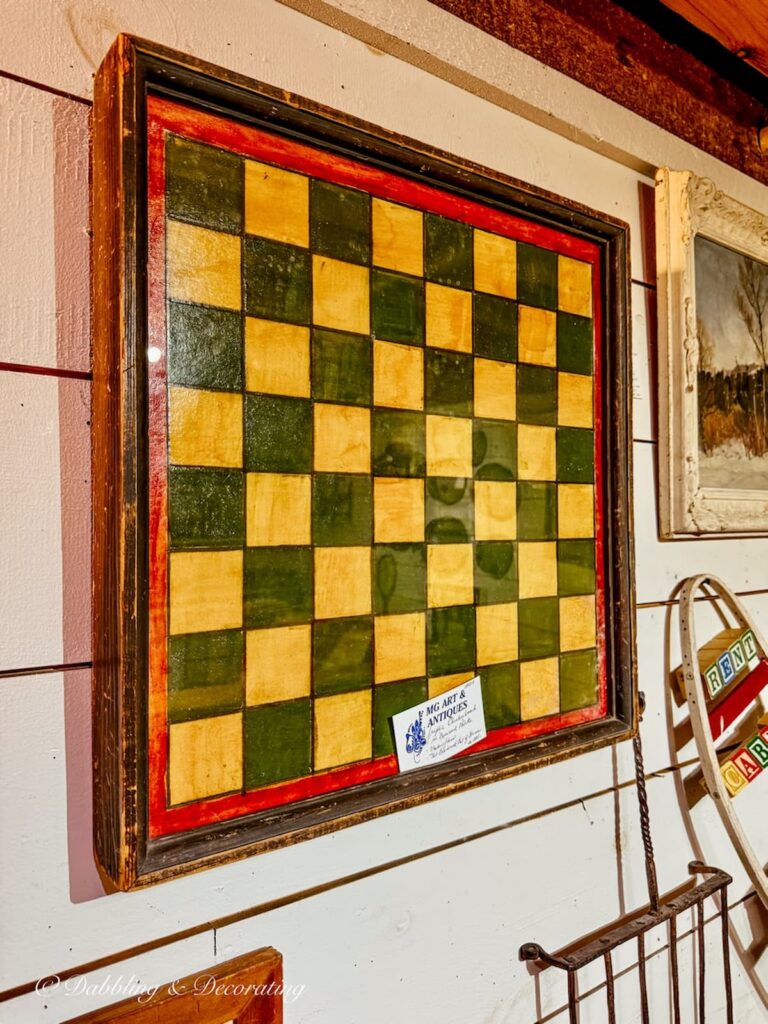 Yellow and green primitive chess board hanging on wall in New England antique store.
