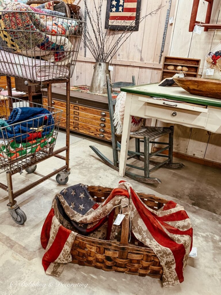 Vintage booth inside antique store in Vermont styled with heritage Americana decor like baskets, flags, quilts, and more.