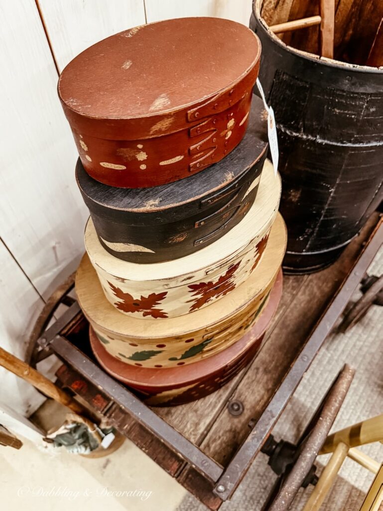 Vintage shaker style pantry boxes stacked on a cart in an antique store for Americana decor.
