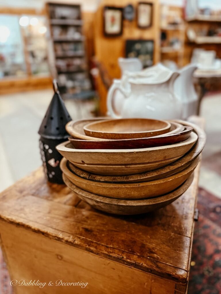 stack of vintage wooden bowls on a wooden bench in antique store.