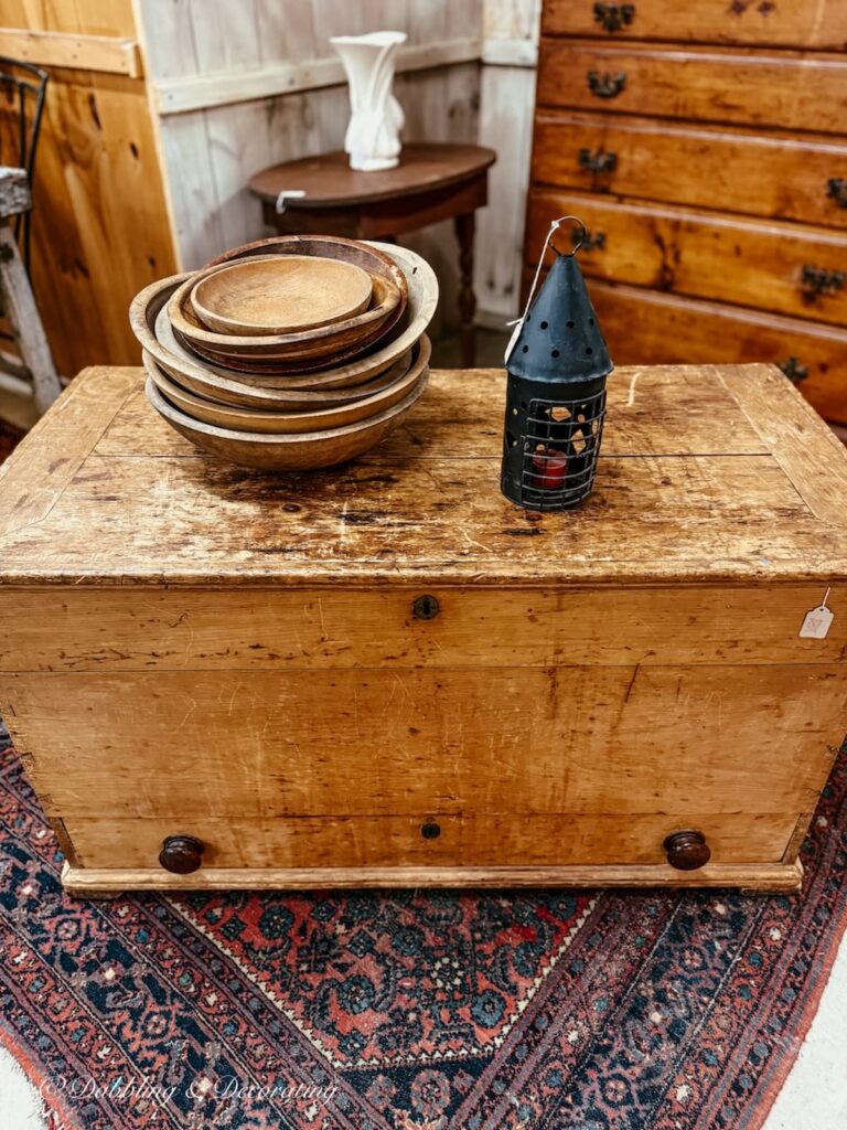 antique wooden trunk with stacks of vintage wooden bowls and black lantern, ideal for heritage Americana decor ideas.