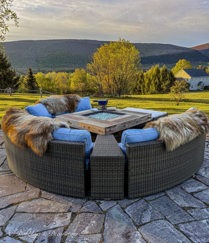 Backyard fire pit patio with sectional seating and blue cushions draped with foxy British sheepskins for spring layering in the mountains.