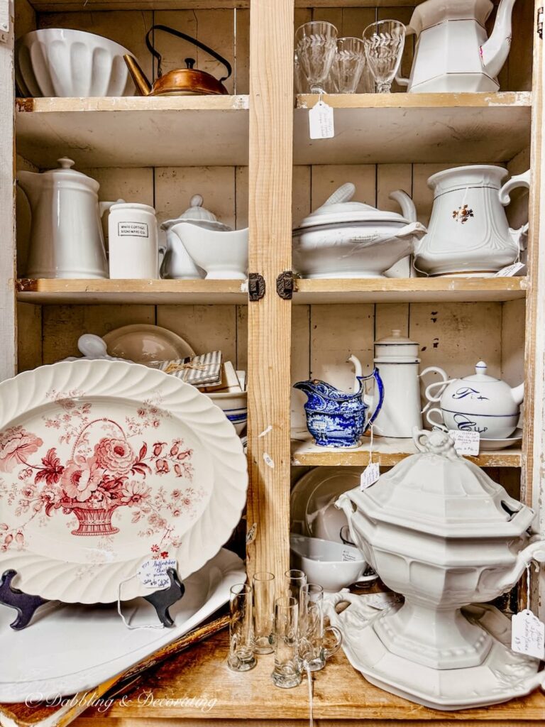 Antique booth in Wells, Maine with white ironstone filling it and a red and white transferware platter ideal for vintage Patriotic place settings.