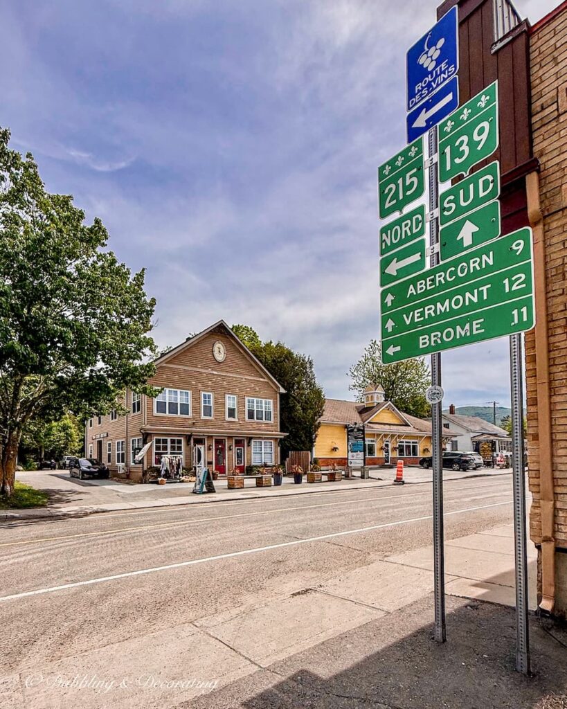 Downtown Sutton, Quebec with road signs to local areas with mileage to Vermont 12 KL.