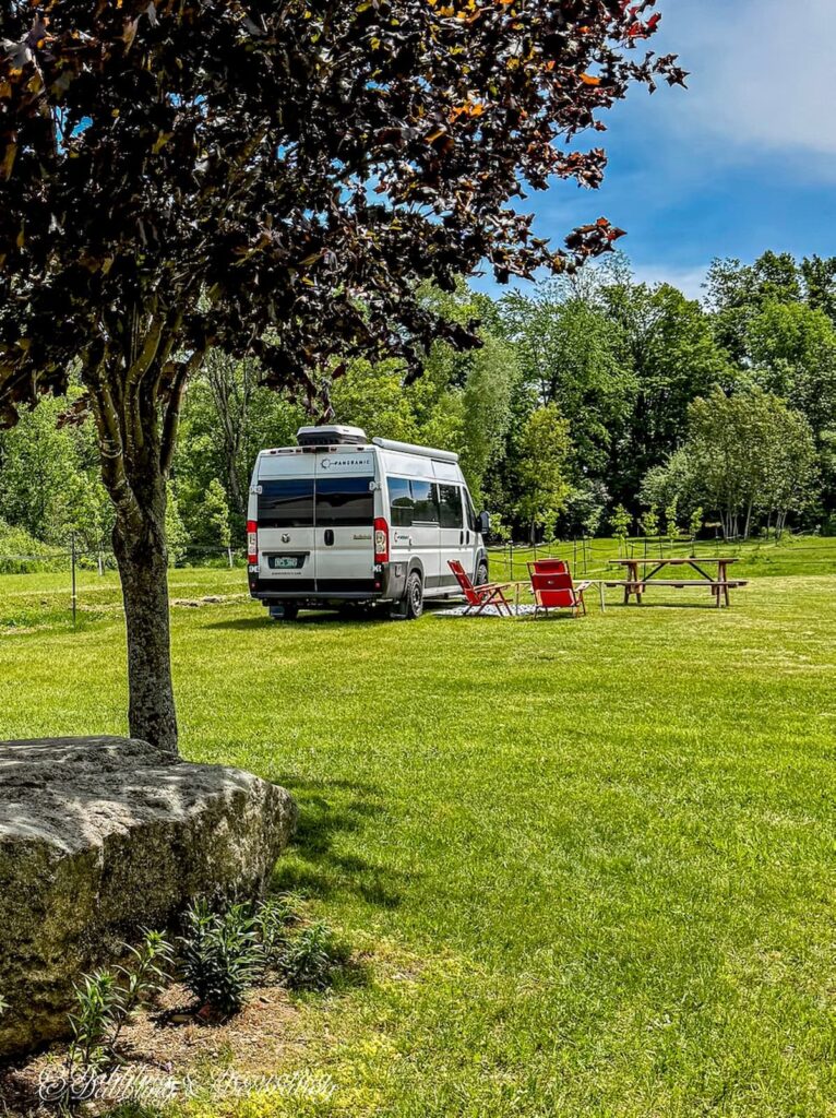 White RV parked with outdoor chairs and table at the Vignoble Domaine Bresee, Sutton, Quebec.
