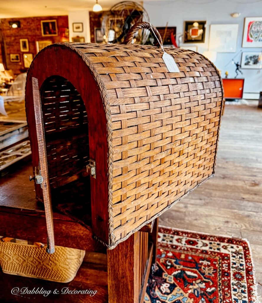 Wicker antique pet carrier on display with open door; decorating with antiques.