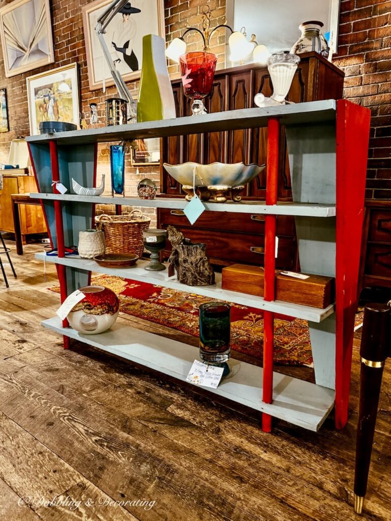 Mid century modern bookcase with open shelving, red and blue vibrant colors decorated with antiques at Open House Portland.