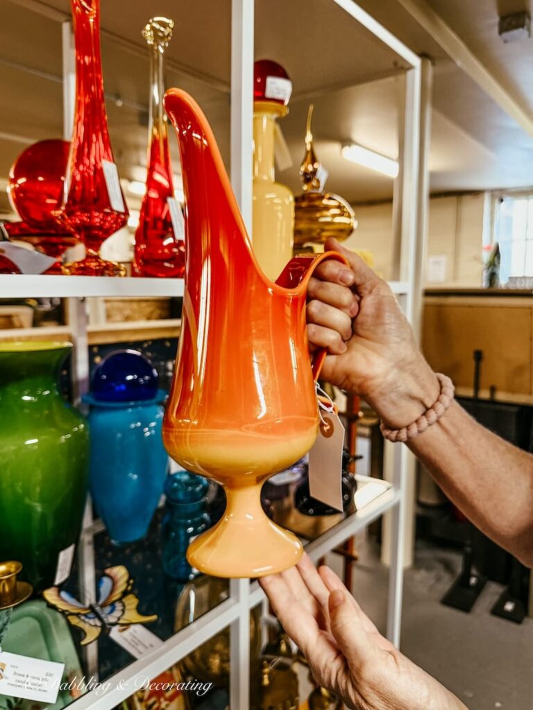 Retro mid century modern orange pitcher in hand at Portland Antiques Mall in Maine.