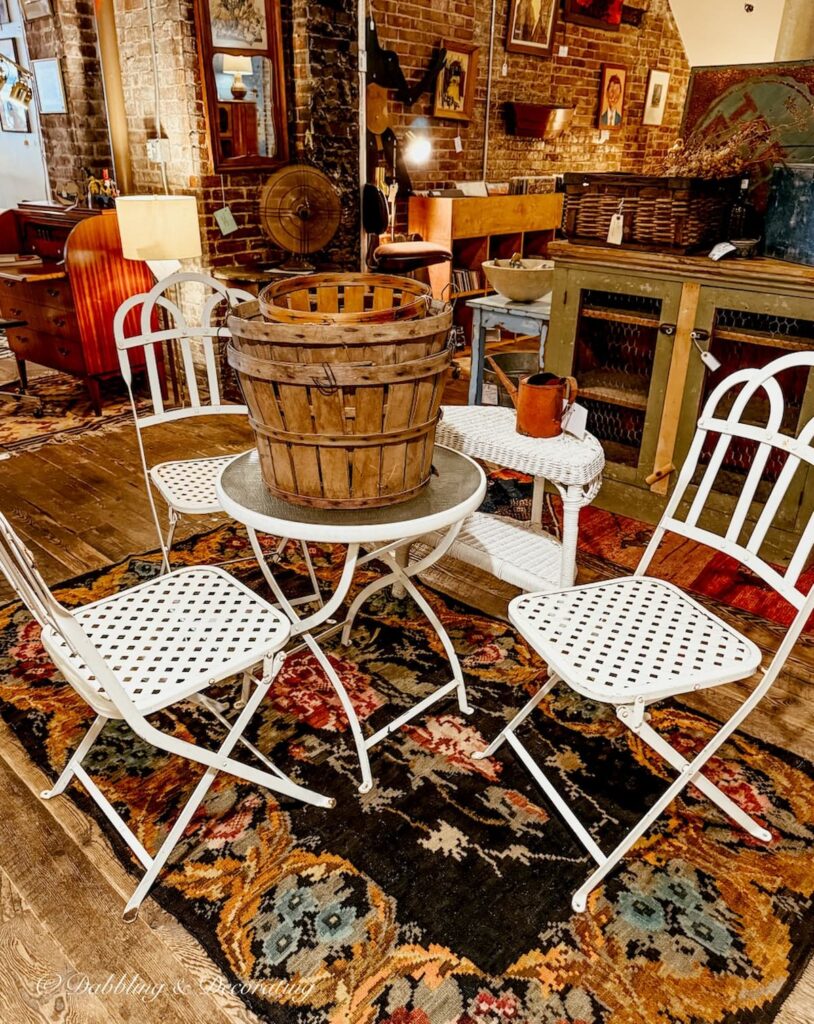 White wrought iron bistro table with chairs paired with antique wooden baskets at Open House Portland decorating with antiques.