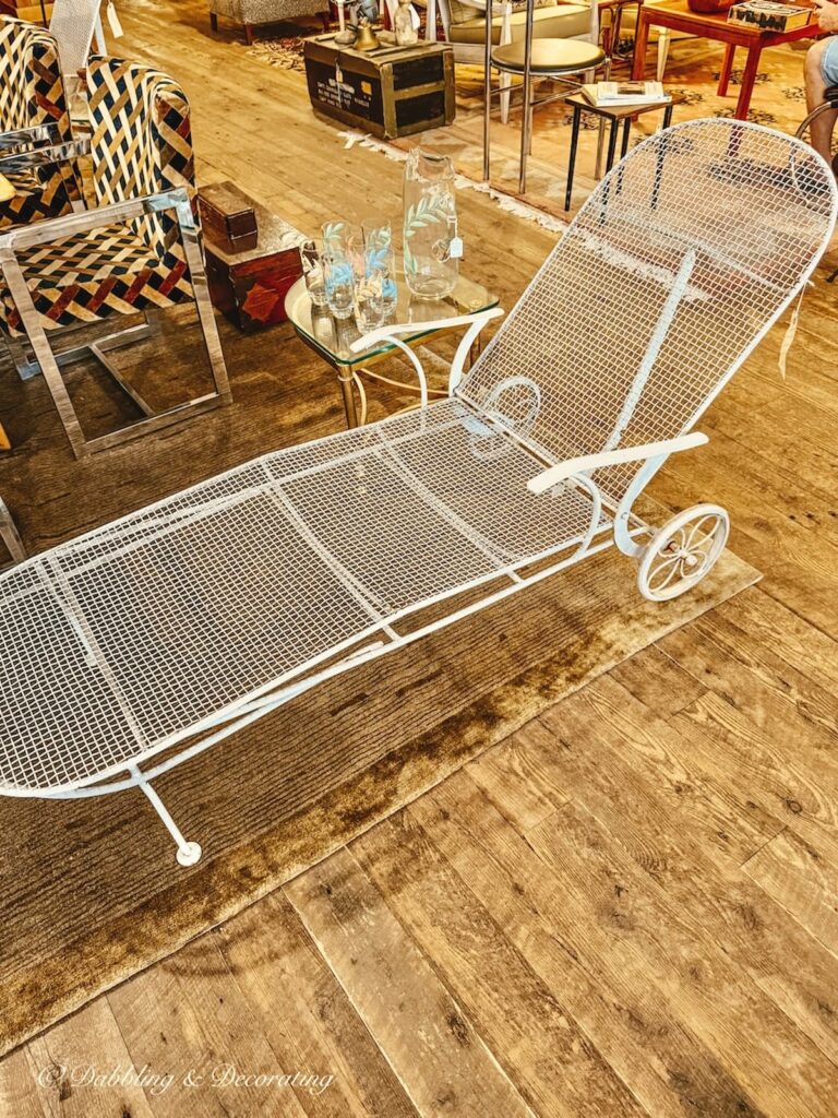 Mid century modern white wrought iron lounge chair with set of retro lemonade set on side table in antique store in Portland, Maine.