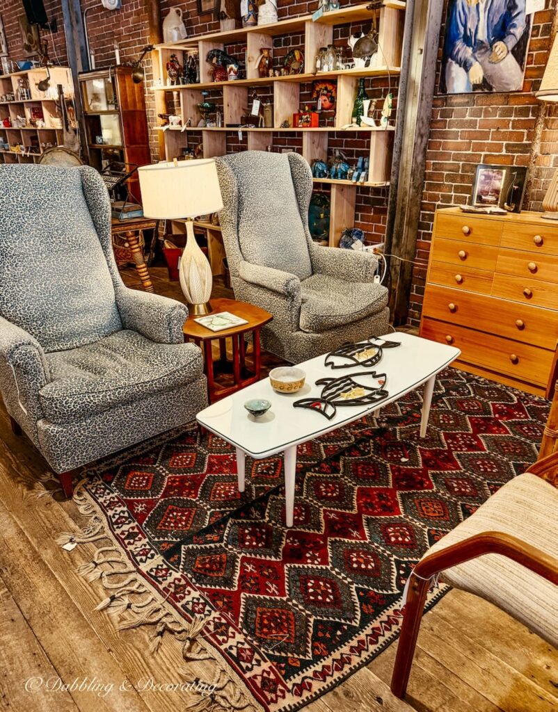 Mid century modern antique booth with red vintage rug and seating area designed beautifully and welcoming at Open House Portland, Maine.