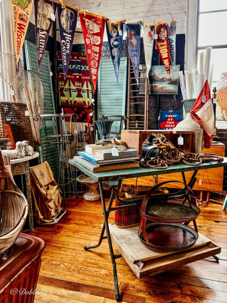Vintage pennants hanging in a vintage booth display from a rope at Portland Antique's Mall in Maine. So Vintage urban for decorating with antiques.
