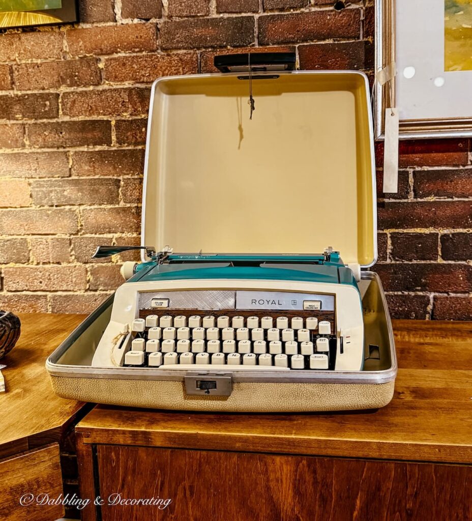Retro turquoise and yellow typewriter in case displayed for decorating with antiques at antique store in Portland, Maine.