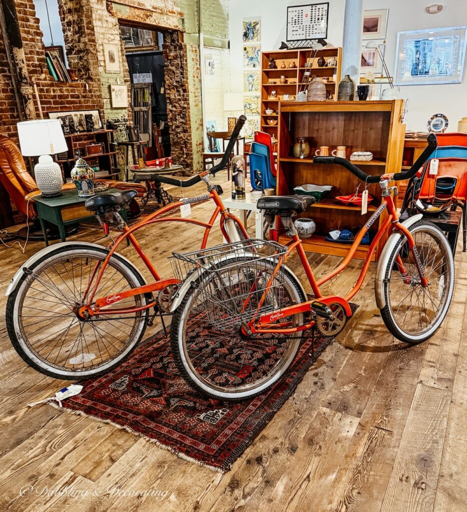 Two old fashioned orange bicycles in antique store in Portland, Maine; decorating with antiques in vintage urban ways.