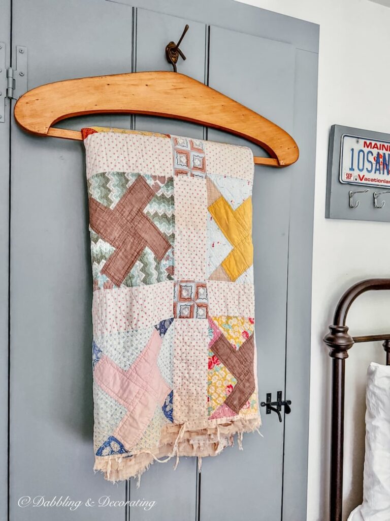 My grandmother's antique quilt hanging on an oversized textile hanger on a bedroom closet door.