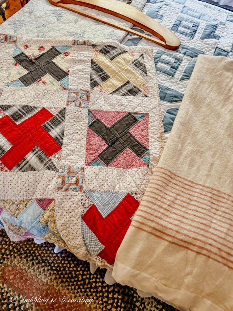 Antique handmade quilt laying on bed next to an antique camp blanket with pink stripes from my parents' attic.