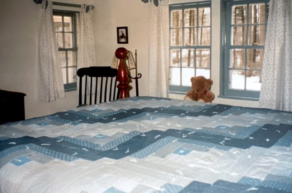 Antique rope bed with handmade blue quilt in small old home's bedroom styled with antiques.