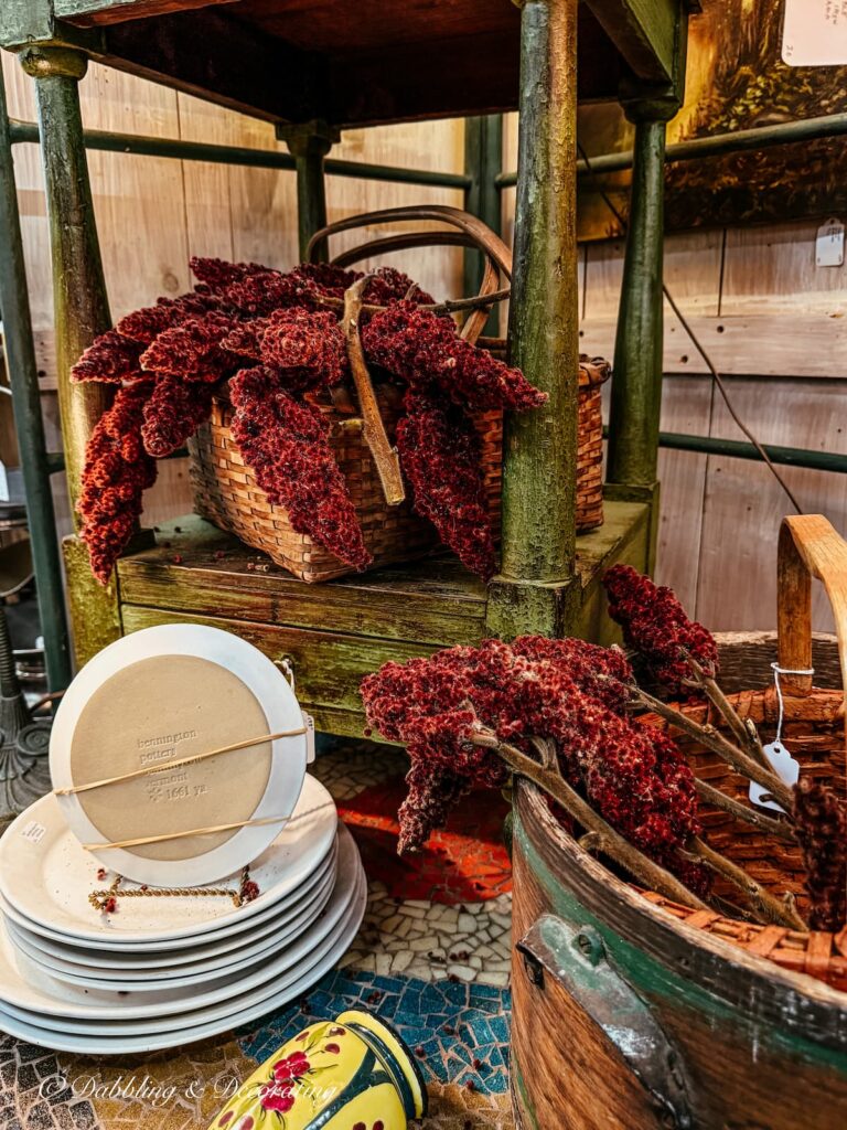 Fall antique booth with antique baskets filled with burgundy dried branches.