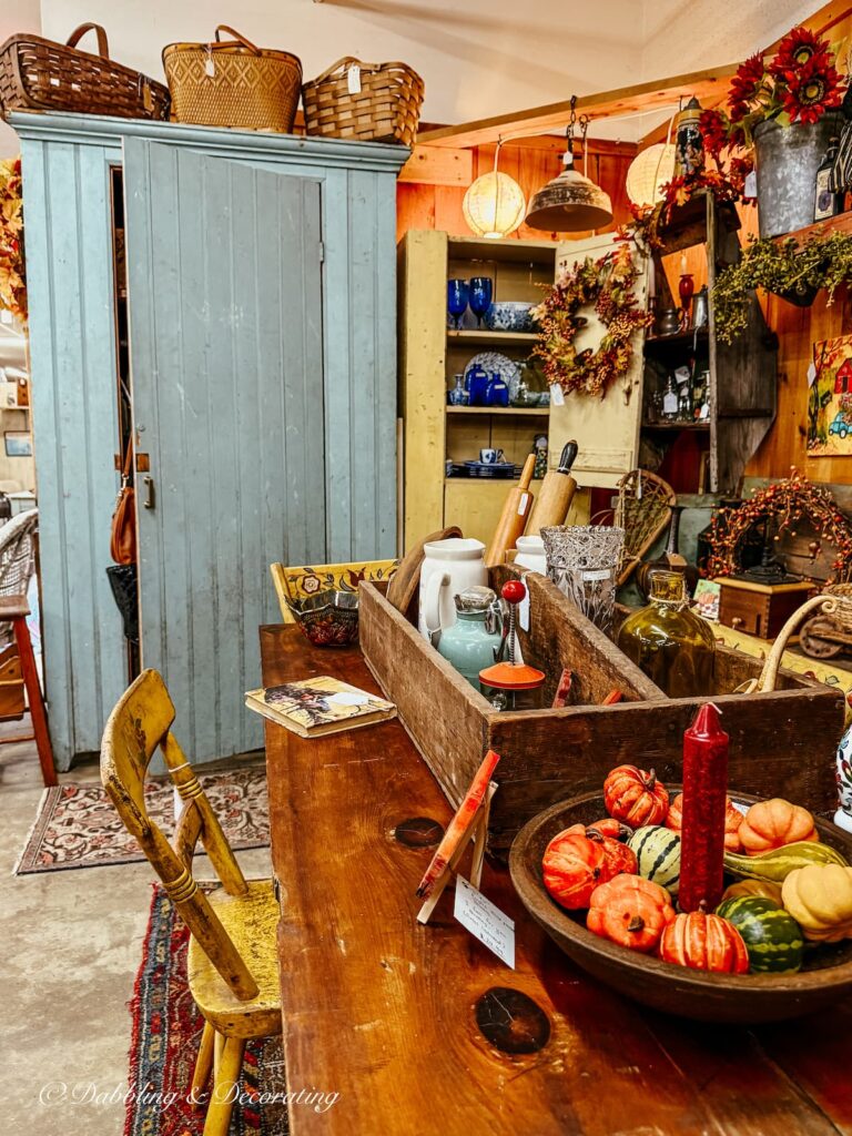 Fall vintage booth display with blue hutch filled with flannel shirts for sale.