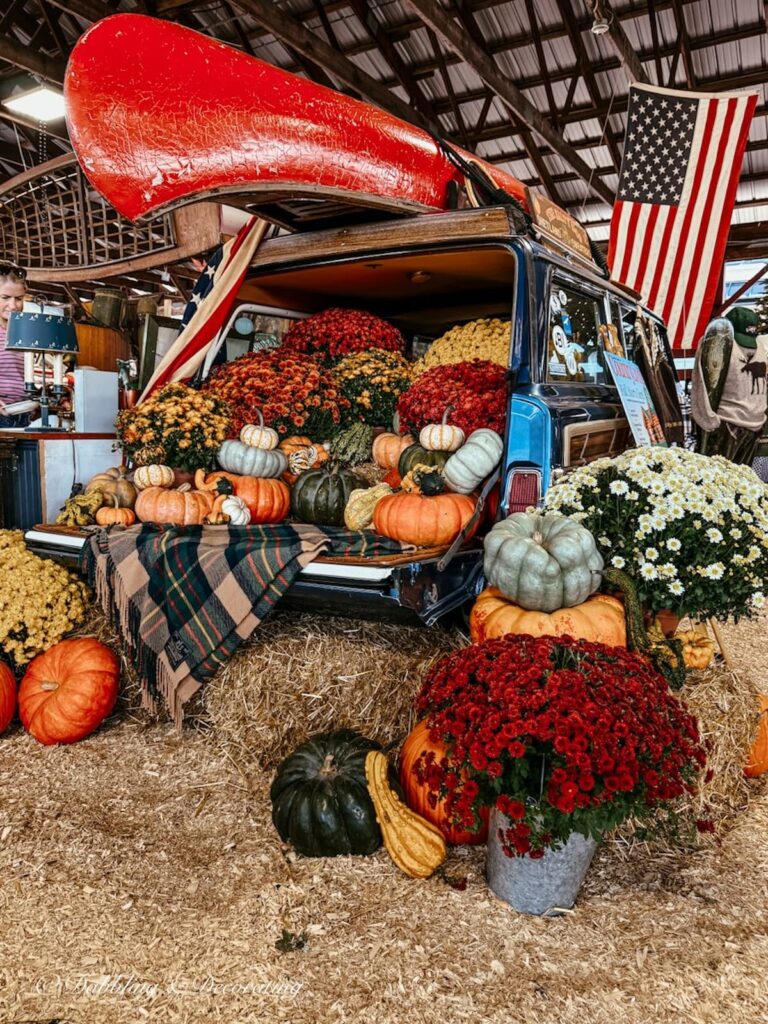 Vintage Wagoneer with trunk filled with pumpkins, gourds, and colorful mums in vintage fall booth display at the Vintage Country Living Fair.
