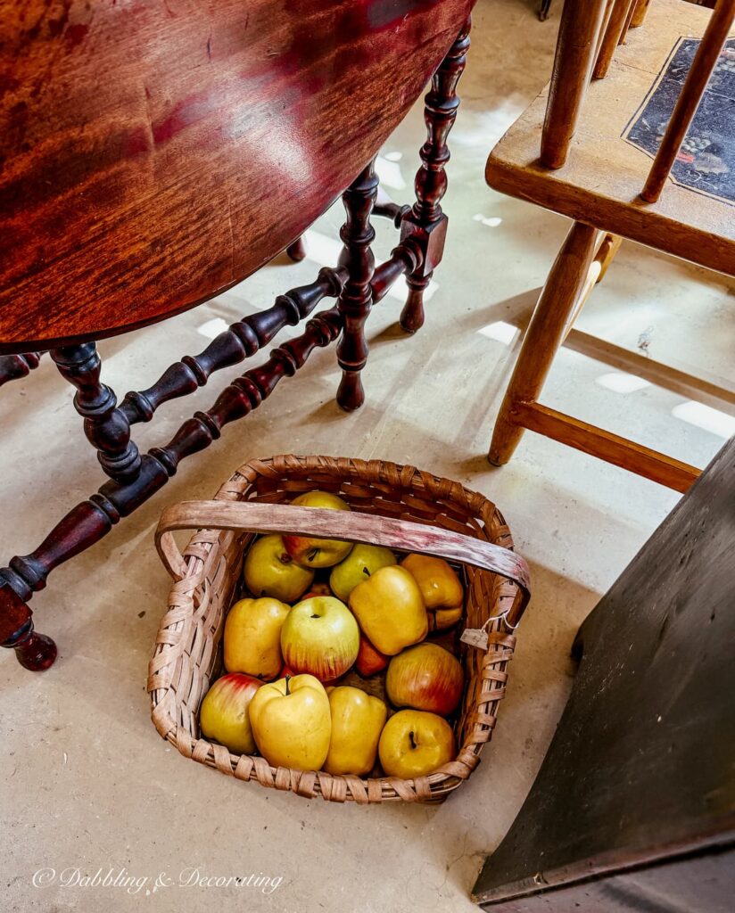 Antique basket on floor filled with apples as a fall vintage booth display. Simple yet makes a statement.