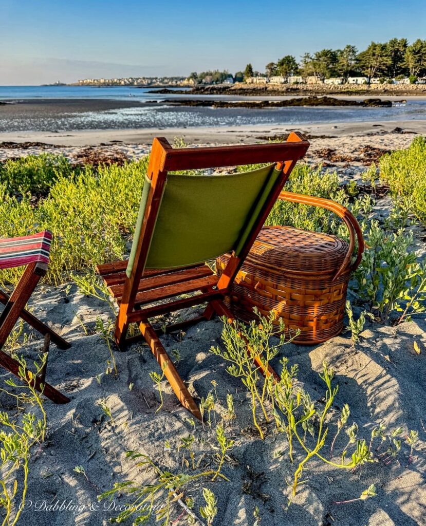 Thrifted retro camp chair with vintage picnic basket on the beach during sunset in Maine.