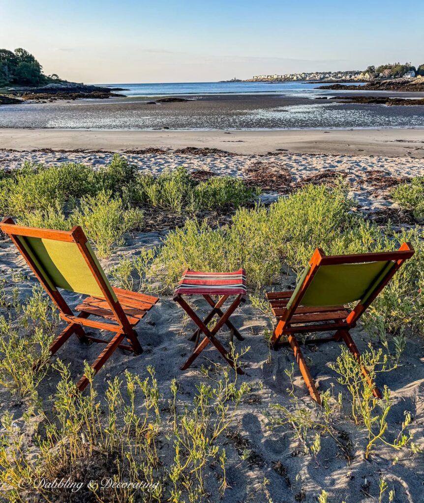 Two retro camp chairs on the beach with a camp stool on the beach at Maine at sunrise.