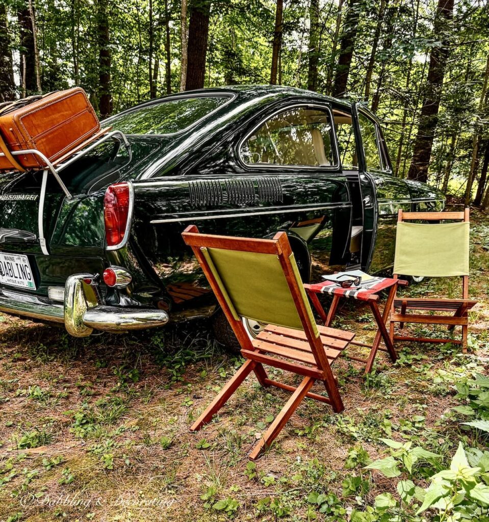 Vintage VW Fastback with two green wooden camp chairs and camping stool on the side of a road on a Sunday drive.